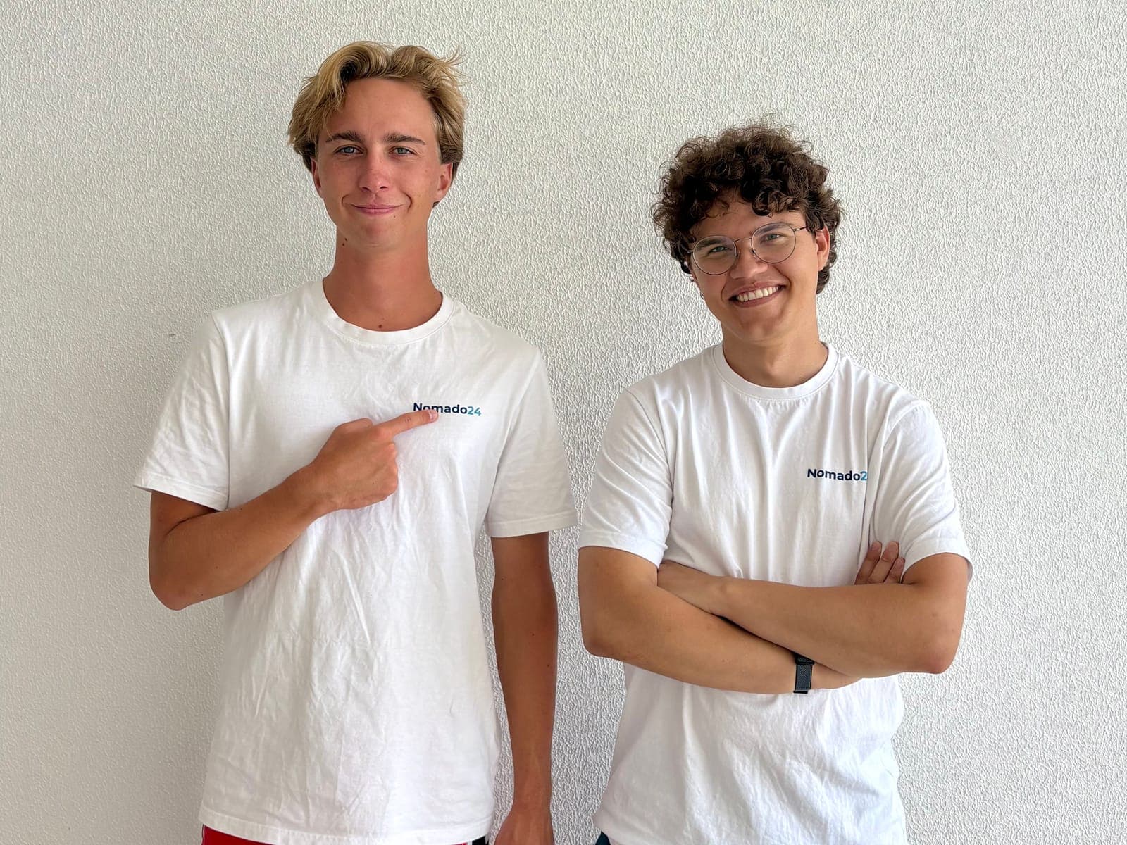 Lars Schreiner zeigt auf das Nomado24-Logo auf seinem Shirt, daneben Anton Petuchow